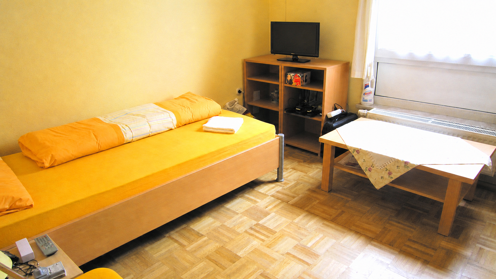 Einzelbettzimmer mit Tisch und Fenster